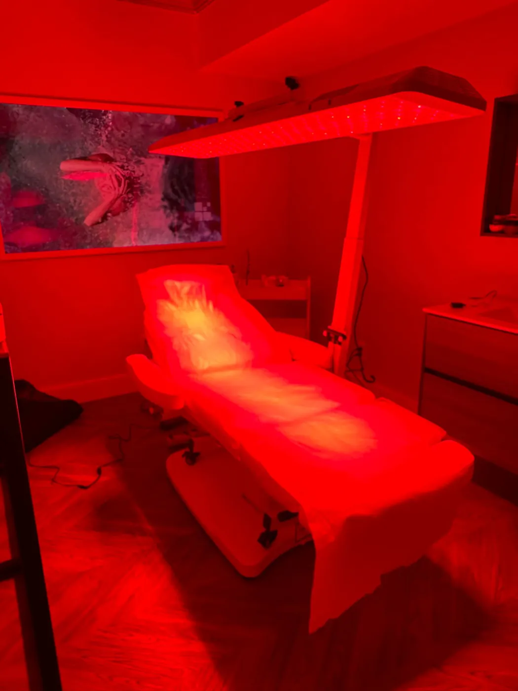A clinic treatment chair positioned under an overhead red light panel